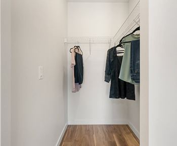 a walk in closet with clothes hanging on a rack